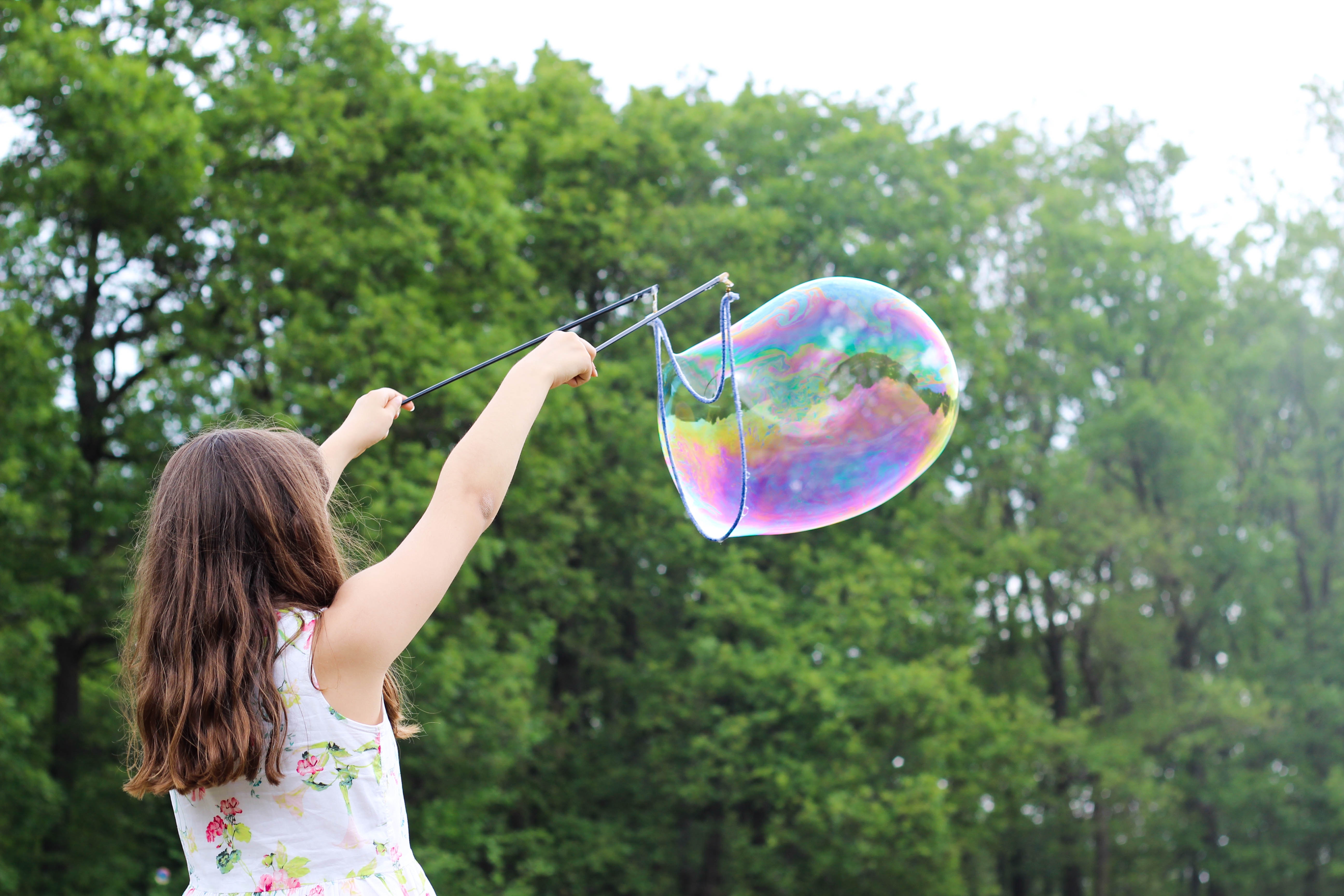 Girl playing outdoors with a bubble blower